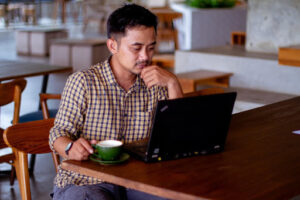 A picture of a person looking at their computer in a coffee shop as they file an online claim with Veritas Global Protection